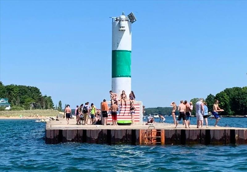 Light house on Portage Lake channel with people